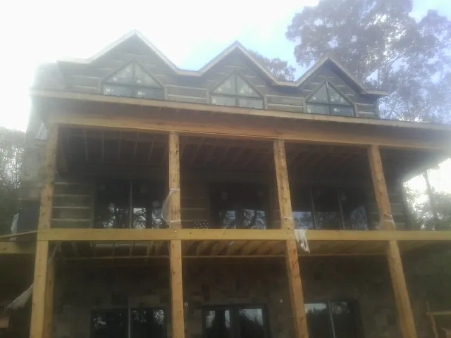 Dormers and porch framing on a large log home under construction — Roof Coating work by our crew in Long Pine