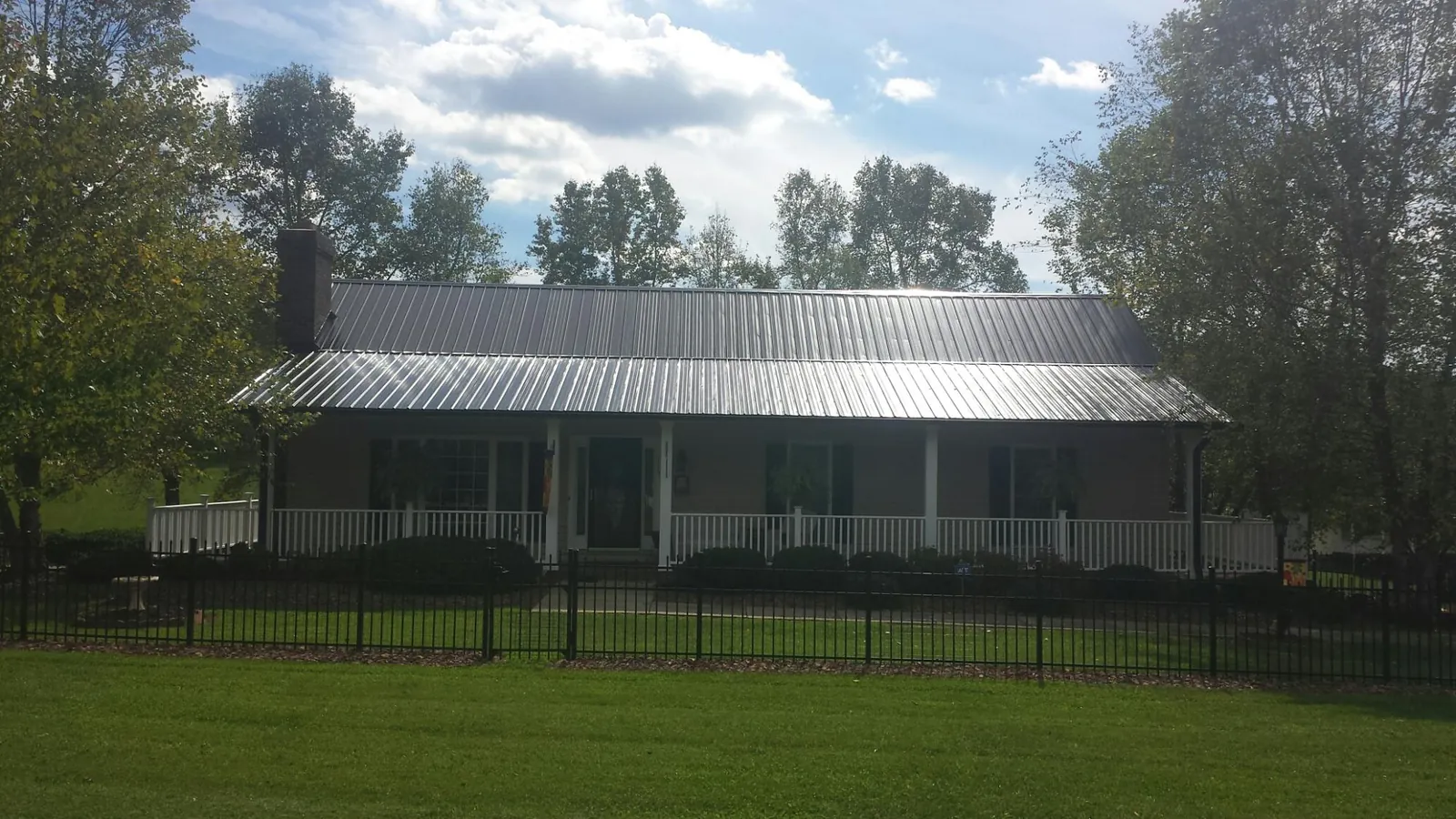 Gray metal roof on a brick ranch with a full width front porch — Gutter Guard Installation work by our crew in Long Pine