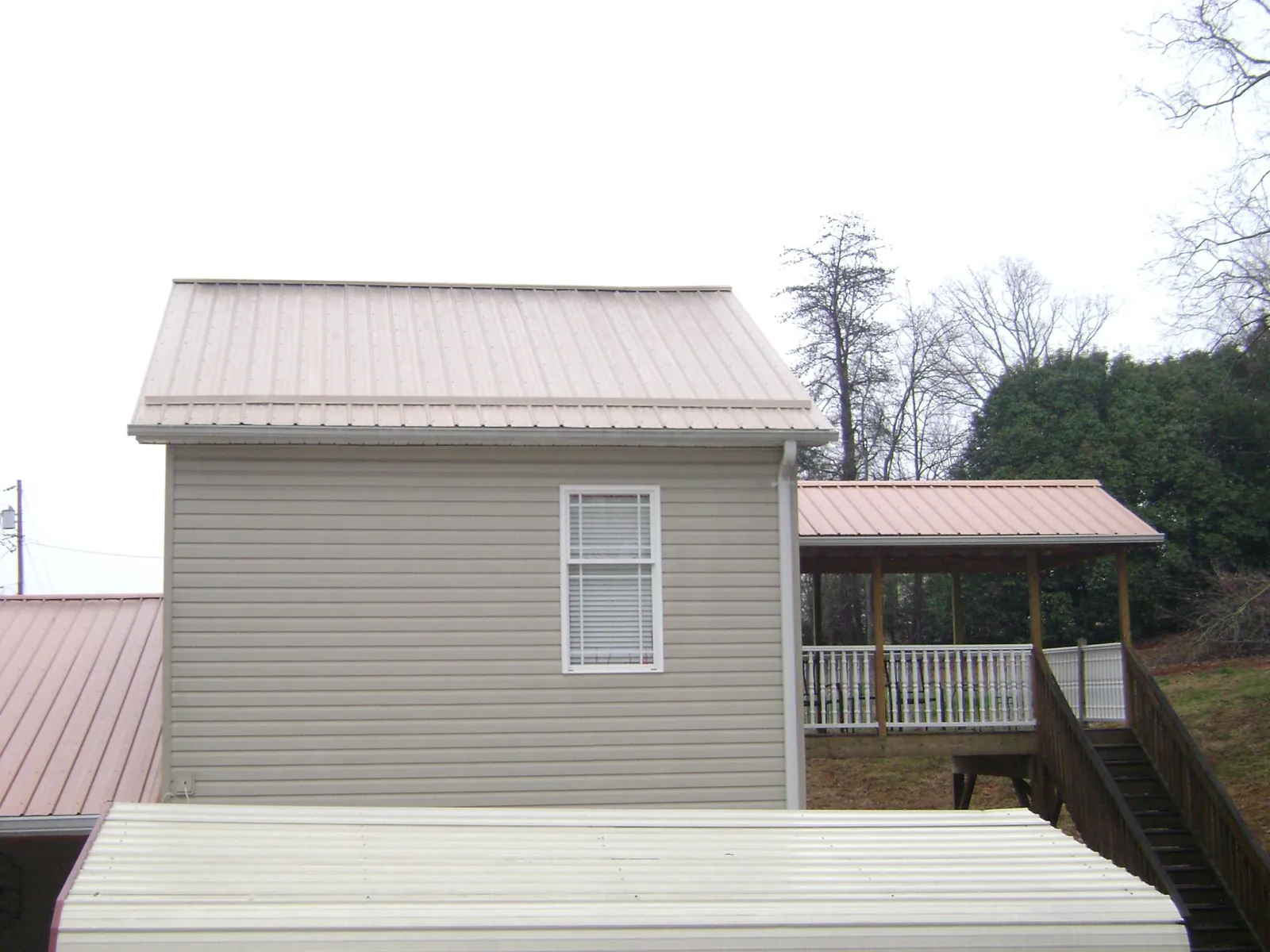 Tan metal roofs on a two story addition and attached porch, from a Roof Replacement job in Long Pine