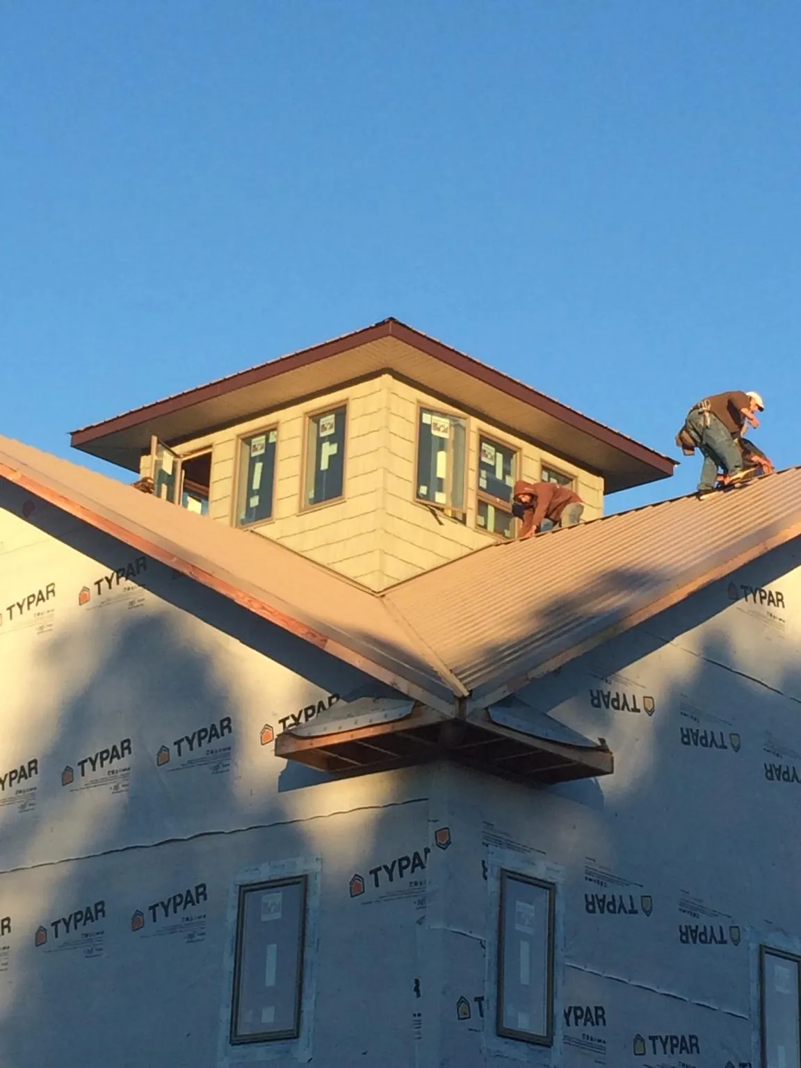 Roofers working around a rooftop cupola on a new metal roof at sunset — Roof Waterproofing in Long Pine by Roofing Brothers